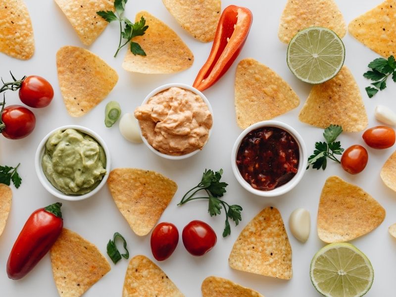 Loaded Nachos Recipe 4 photo of chips surrounded by dips and vegetables showing ingredients for loaded nachos recipe