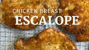 banner image of crispy chicken escalope - close up of crispy fried chicken with herbs on a drying rack topped with flaky salt